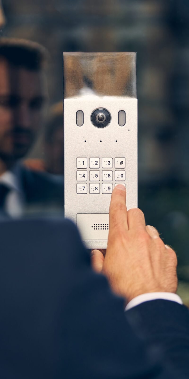 Brunette male in official clothes staing outside while pressing key for door to open