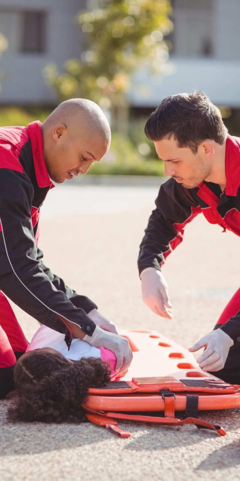 Paramedics putting injured girl onto a backboard on street